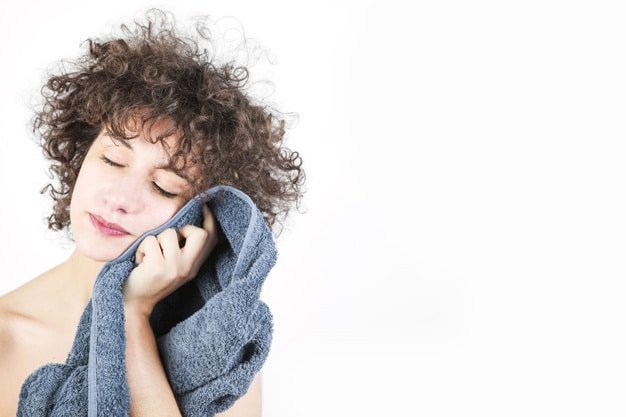 young woman wipes her face with towel