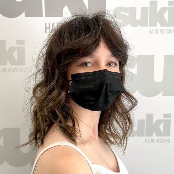 Curtin Fringe Wolf Haircut - a woman wearing a white sleeveless top and is wearing a facemask