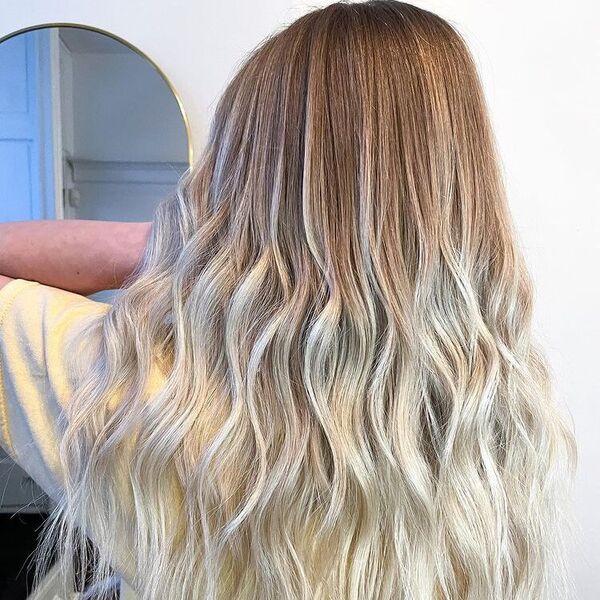 Brown and Platinum Blonde Balayage - a woman holding her hair and is wearing a yellow shirt