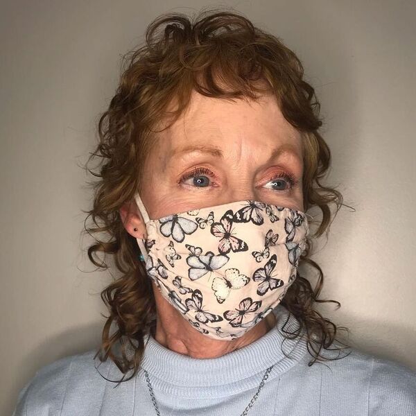 Curl Mullet on Women over 50 - a woman wearing butterflies mask and pastel blue top.