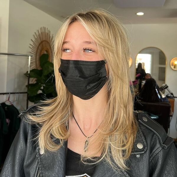 Curtain Bangs Blonde Balayage - a woman wearing a black leather jacket and a facemask