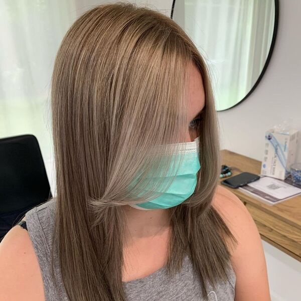 Curtain Bangs with Bronde Hairstyle - a woman wearing an apricot colored facemask