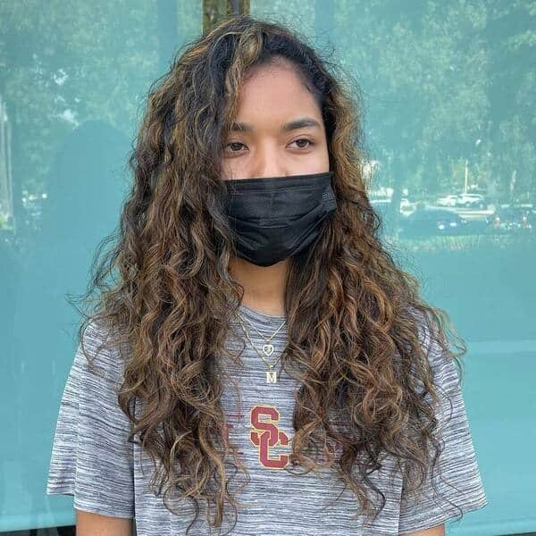 Natural Curly Hair in Chunky Highlights - a woman wearing black mask with layers of necklace.