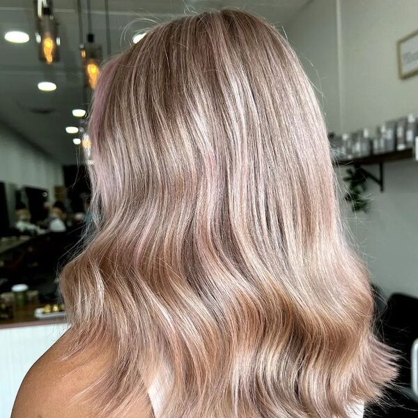 Pink Tinted Blonde Balayage - a woman in a salon wearing a white sleeveless top