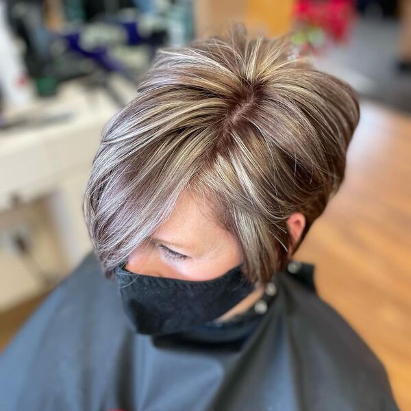 Pixie Cut with Blonde Highlights -an old woman wearing a black cape and a facemask
