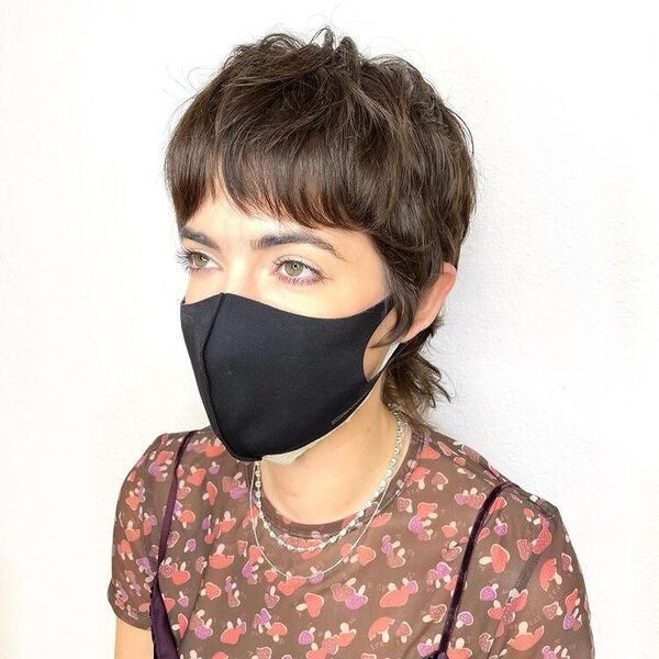 Pixie Mullet with Short Curtain Bangs - a woman wearing a printed shirt and a black facemask