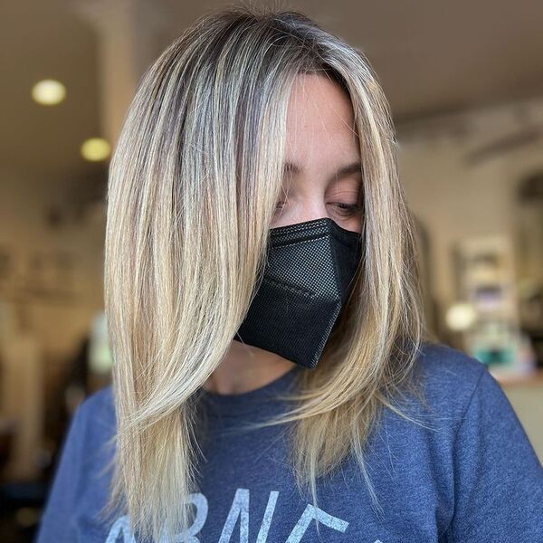 Rooted Hair Blonde Balayage - a woman wearing a dark blue shirt and a black facemask