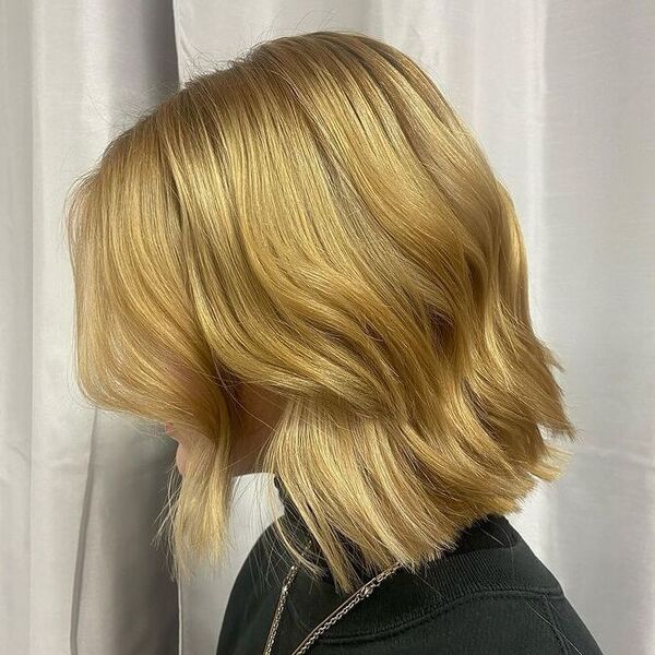 Wavy Classic Blonde Bob with Fringes - a woman wearing a layered silver necklace.