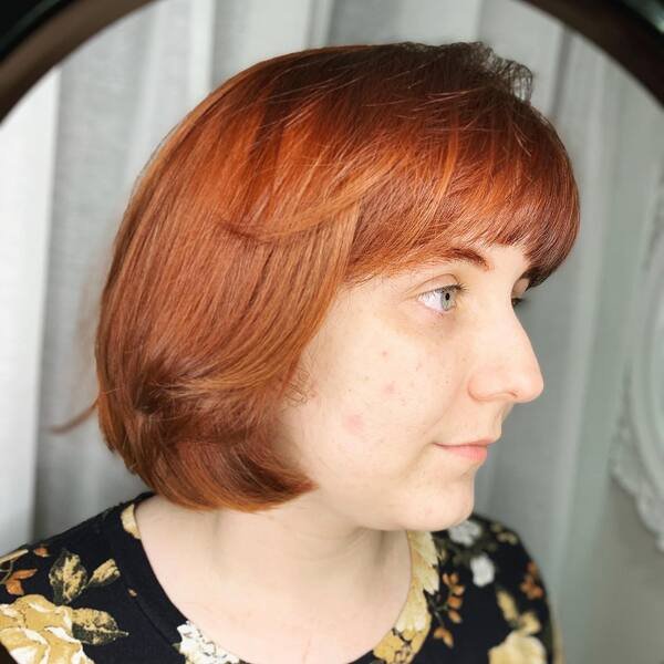 Copper Bob with Classic Bangs - a woman wearing black floral top.