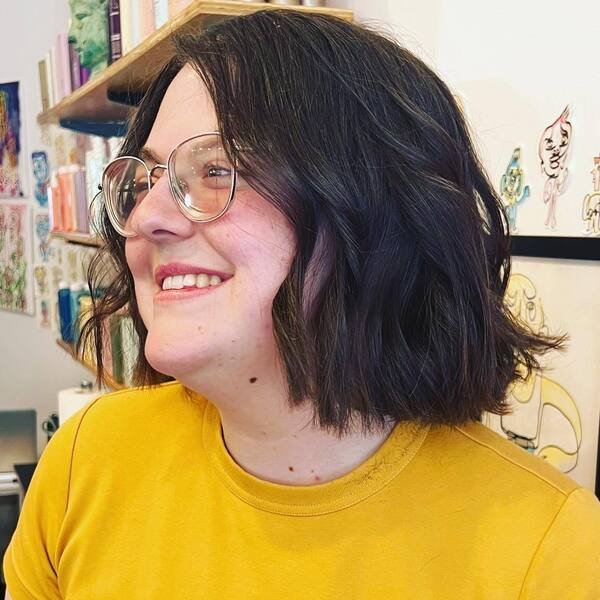 Curled Neat Short Haircut - a woman wearing bright yellow shirt.
