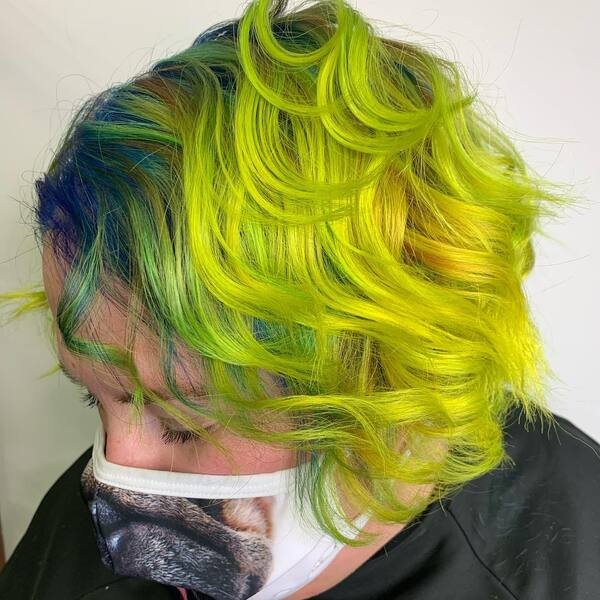 Neon Green Curly Pixie - a woman wearing mask and black barber cape.
