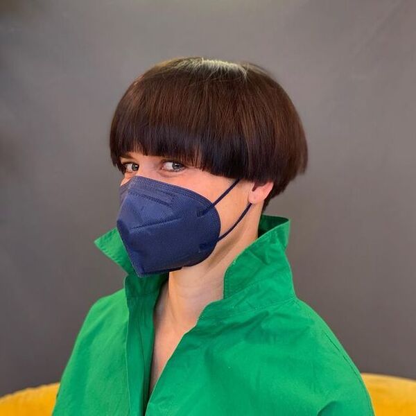 a woman wearing green polo and blue mask