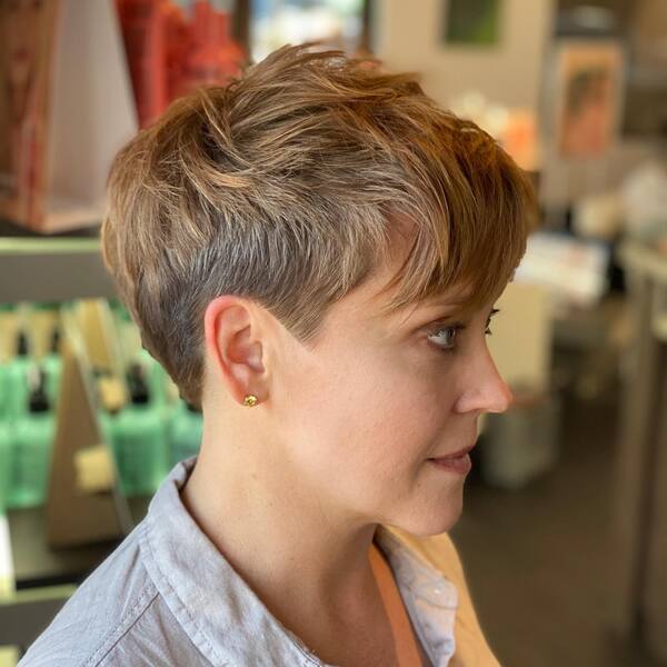 Edgy Pixie Cut with Side Bangs - a woman wearing a gold earrings