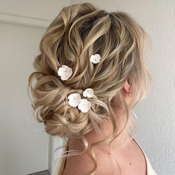 Loose Updo Bun with Flowers - a woman wearing a off shoulder dress
