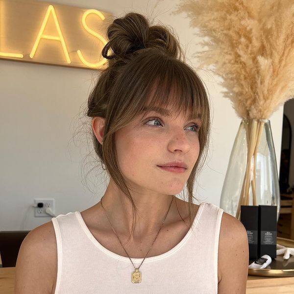 Top Knot Bun with Wispy Bangs - a woman wearing a gold necklace