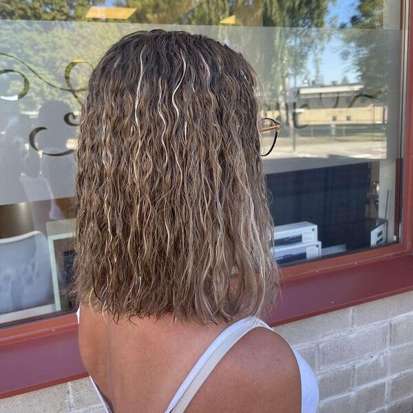 Medium Perm Hair with Highlights - a woman wearing a white top