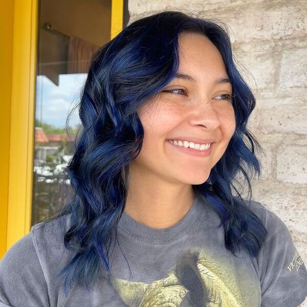 a woman wearing a gray shirt has a dark blue haircolor