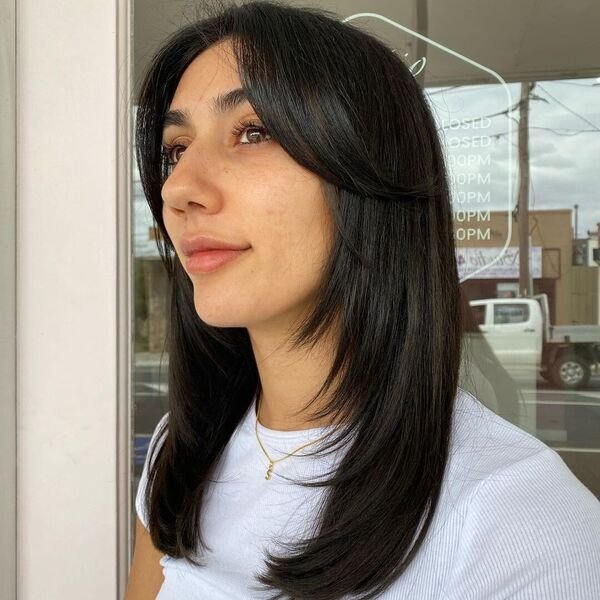 A woman wearing knitted white top and gold necklace with her wash and go hairstyles