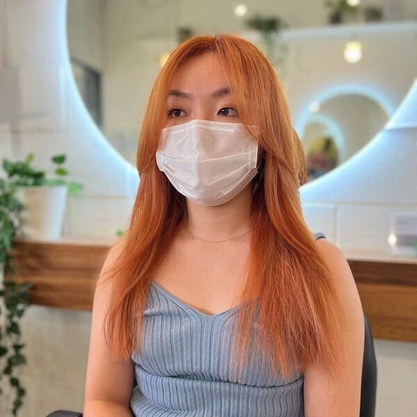 A woman wearing white mask and knitted sleeveless light blue