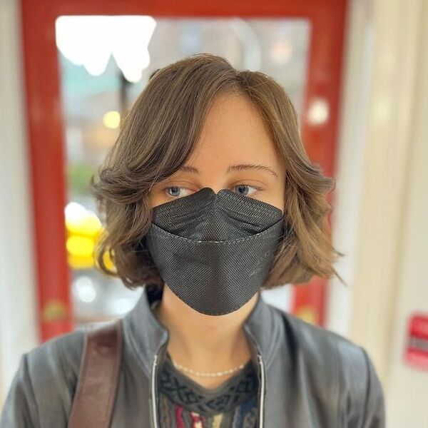 a woman with black facemask wearing a black leather jacket