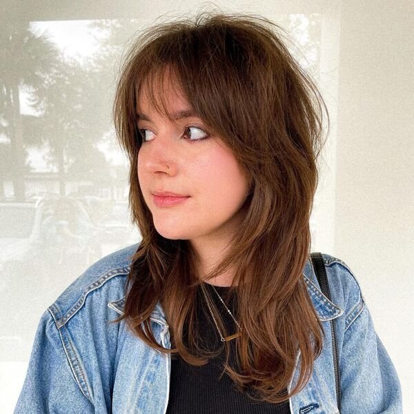 A woman wearing a denim jacket and black knitted top