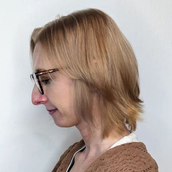 A woman wearing eyeglasses and knitted brown top