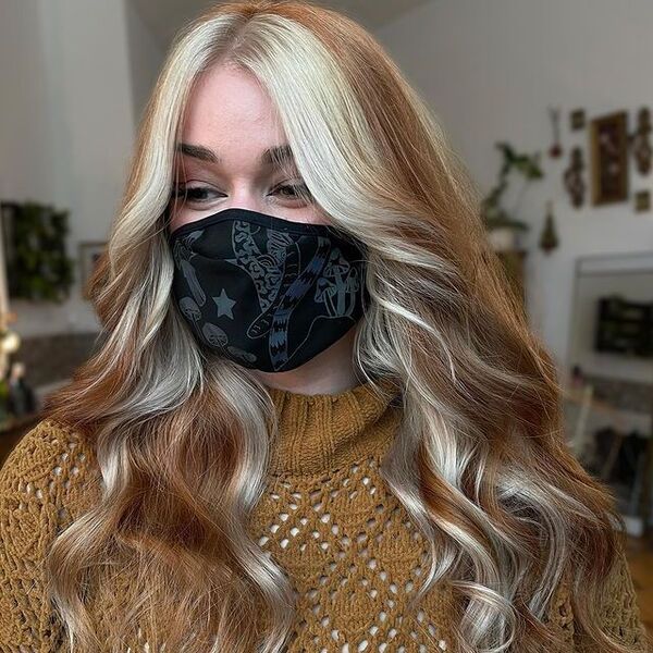 a woman with black printed facemask wearing a brown knitted longsleeve