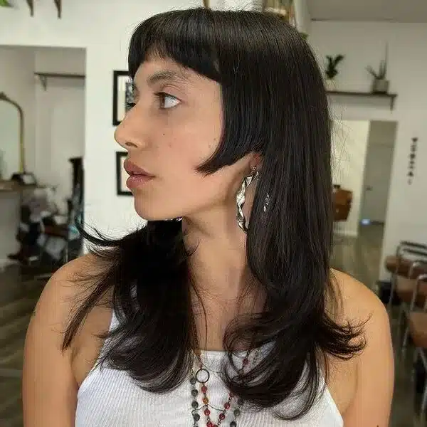 a woman inside a salon wearing a earrings, necklace, and white sleeveless top
